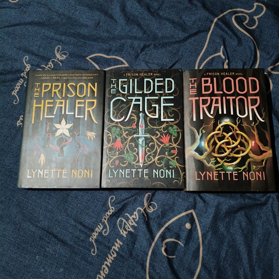 The Prison Healer Trilogy Hardcovers by Lynette Noni (Category: Storybooks) located in Santo Domingo. Submitted by rajjinni (Listing ID 1469060406, Image 1). Description: - Title: The Prison Healer Trilogy by Lynette Noni - Books included: The Prison Healer, The Gilded Cage, The Blood Traitor - Format: Paperback, selling as a complete set - Condition: Covers intact with minimal shelf wear; note that there is some yellowing and foxing on the page 