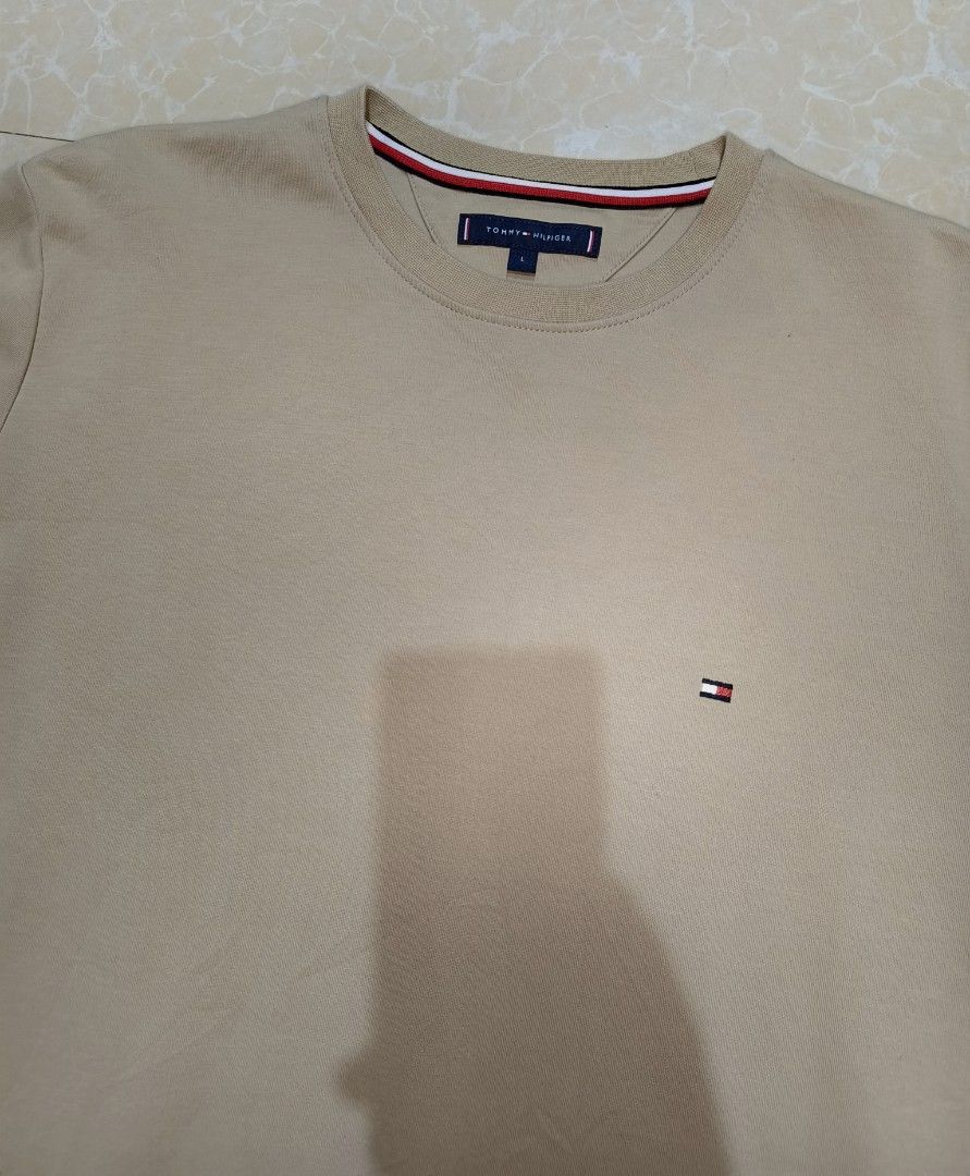 Tommy Hilfiger Beige Sweatshirt Size L (Category: Coats, Jackets and Outerwear) located in Manila. Submitted by purefire-477a (Listing ID 1469078022, Image 3). Description: Tommy Hilfiger crewneck sweatshirt in a clean beige colorway. Size large tag attached at the inner collar with signature red, white, and blue taping. Small embroidered flag logo on the left chest. Ribbed cuffs, hem, and collar keep their shape well. Soft cotton blend material.