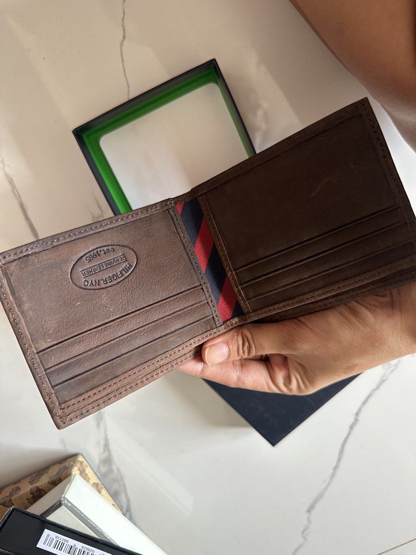 Tommy Hilfiger Brown Leather Bifold Wallet with Box (Category: Wallets & Card Holders) located in Vinzons. Submitted by melodylarg85741 (Listing ID 1468977911, Image 2). Description: - Brand: Tommy Hilfiger - Material: Genuine brown leather - Design: Bifold with embossed front logo and brand hardware detail - Interior: Multiple card slots and trendy striped fabric lining - Special Detail: Est. 1985 stamp inside - Packaging: Includes original blac