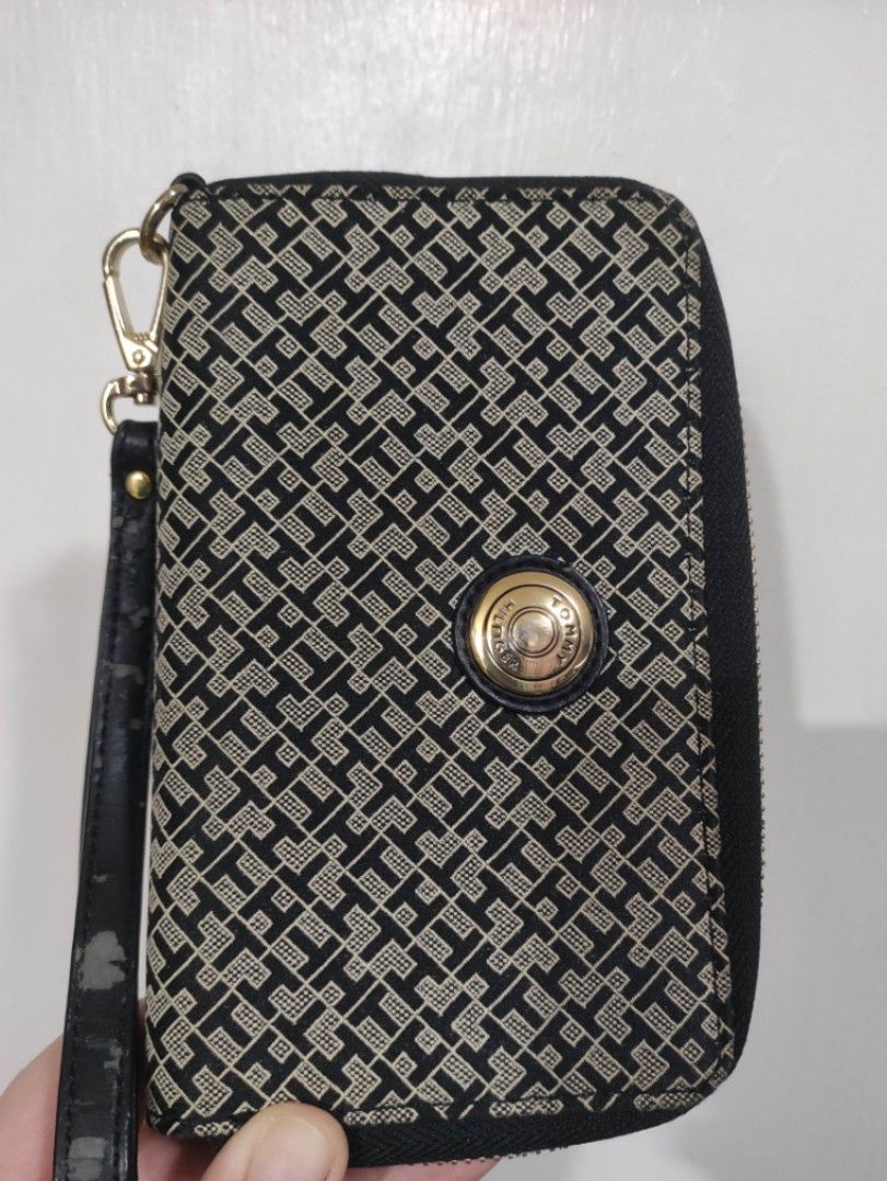 Tommy Hilfiger Monogram Wristlet Wallet (Category: Wallets & Card holders) located in Quezon City. Submitted by pprzi_89 (Listing ID 1469134982, Image 1). Description: pay for shipping fee - Brand: Tommy Hilfiger - Design: Black and beige monogram pattern with gold-tone hardware - Closure: Smooth zip-around closure - Interior: Multiple card slots and compartments lined with dark fabric - Extra Feature: Includes a detachable wrist strap (Note: not