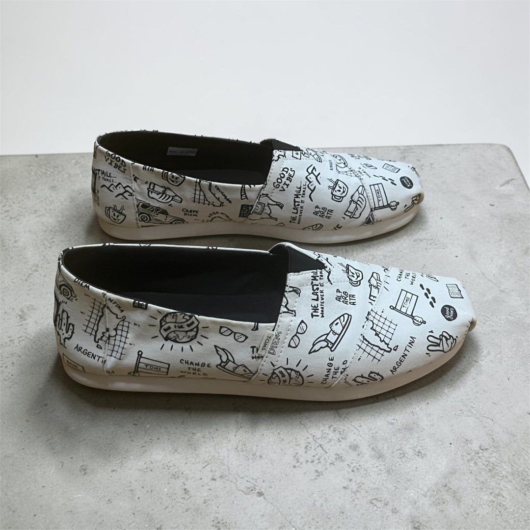 Toms Alpargata Slip-Ons Size 9 (Category: Slippers & Slides) located in Manila. Submitted by chococoffeeboy (Listing ID 1468995566, Image 2). Description: - Toms Alpargata canvas slip-on shoes - Design: White with all-over black doodle sketches, text graphics, and palm tree drawings - Condition: Clean insoles with light wear on the outer soles - Perfect for: Easy, casual everyday outfits Payment: Gcash/Maya Buyer shoulders shipping .