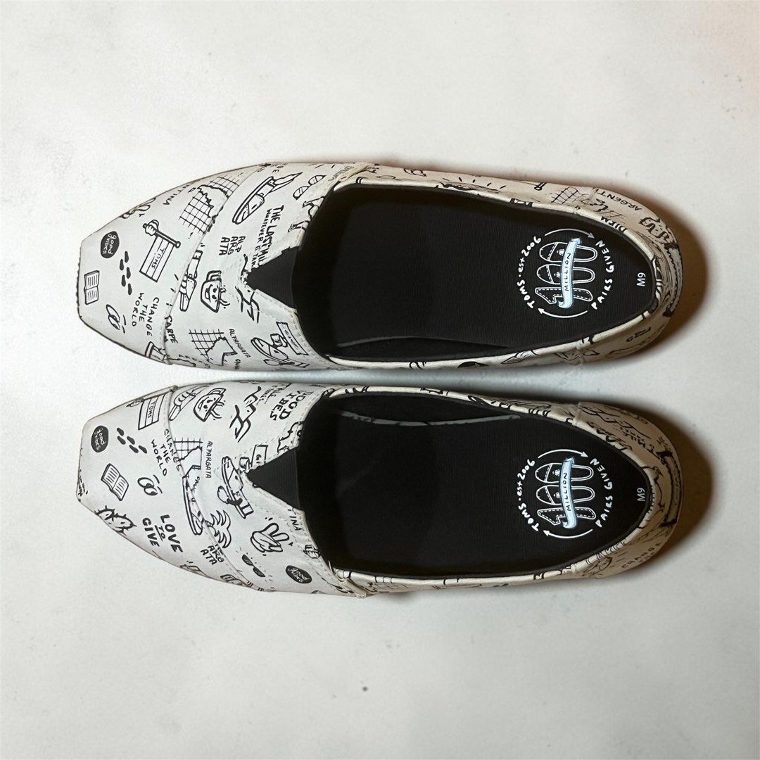 Toms Alpargata Slip-Ons Size 9 (Category: Slippers & Slides) located in Manila. Submitted by chococoffeeboy (Listing ID 1468995566, Image 3). Description: - Toms Alpargata canvas slip-on shoes - Design: White with all-over black doodle sketches, text graphics, and palm tree drawings - Condition: Clean insoles with light wear on the outer soles - Perfect for: Easy, casual everyday outfits Payment: Gcash/Maya Buyer shoulders shipping .