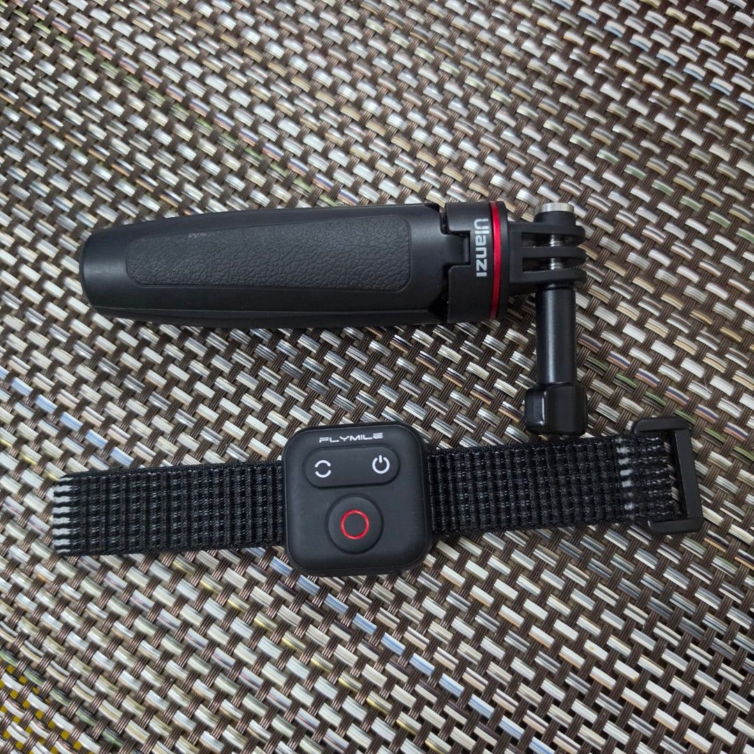 Ulanzi hand grip and Flymile remote control (Category: Tripods & Monopods) located in Quezon City. Submitted by littlemissrafaella (Listing ID 1468963031, Image 1). Description: - Brand/Item: Ulanzi black hand grip with standard action camera mount - Included: Flymile black remote controller with power, sync, and red record buttons - Convenience: Attached to a secure black fabric wrist strap with buckle closure - Condition: Clean and well-maintai