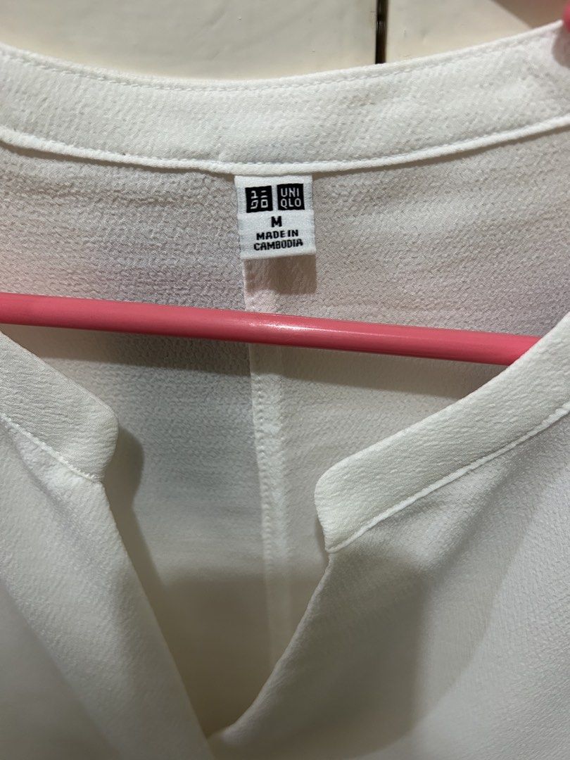 Uniqlo White Blouse (Category: Blouses) located in Manila. Submitted by ab.mendoza (Listing ID 1468977040, Image 2). Description: - Brand: Uniqlo - Size: M - Color: White - Fit: Loose, relaxed fit - Design: Deep V-neckline with front center pleat - Sleeves: Short sleeves - Fabric: Light and breezy - Style: Great for smart casual wear or office outfits; easy to pair with trousers or skirts.
