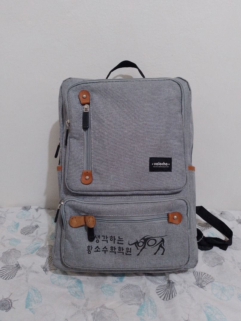 Veloche Grey Canvas Laptop Backpack (Category: Backpacks) located in Imus. Submitted by bestfinds_yeth0724 (Listing ID 1469153579, Image 1). Description: Grey canvas backpack from Veloche. Has brown faux leather accents, multiple zippered exterior pockets, and a top grab handle. Inside has a padded laptop sleeve with a velcro strap. Back straps are adjustable and padded. Korean text printed on the lower front pocket. MOP gcash Issue; please refer