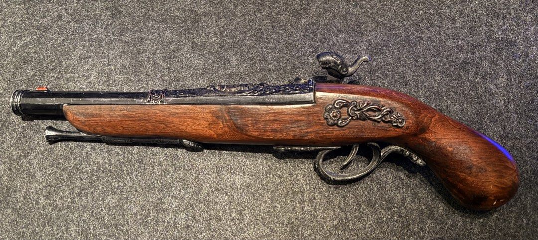Vintage LIGHTER Replica Flintlock Pirate Pistol (Category: Vintage Collectibles) located in Manila. Submitted by grandpenguin0925 (Listing ID 1469157377, Image 1). Description: - Type: Decorative flintlock pistol LIGHTER - Finish: Wood grain stock with ornate metal engravings - Features: Working hammer mechanism, brass-tone screws, and attached ramrod - Material: Solid weight, highly detailed casting Working flint/ignition Need lighter fluid/buta