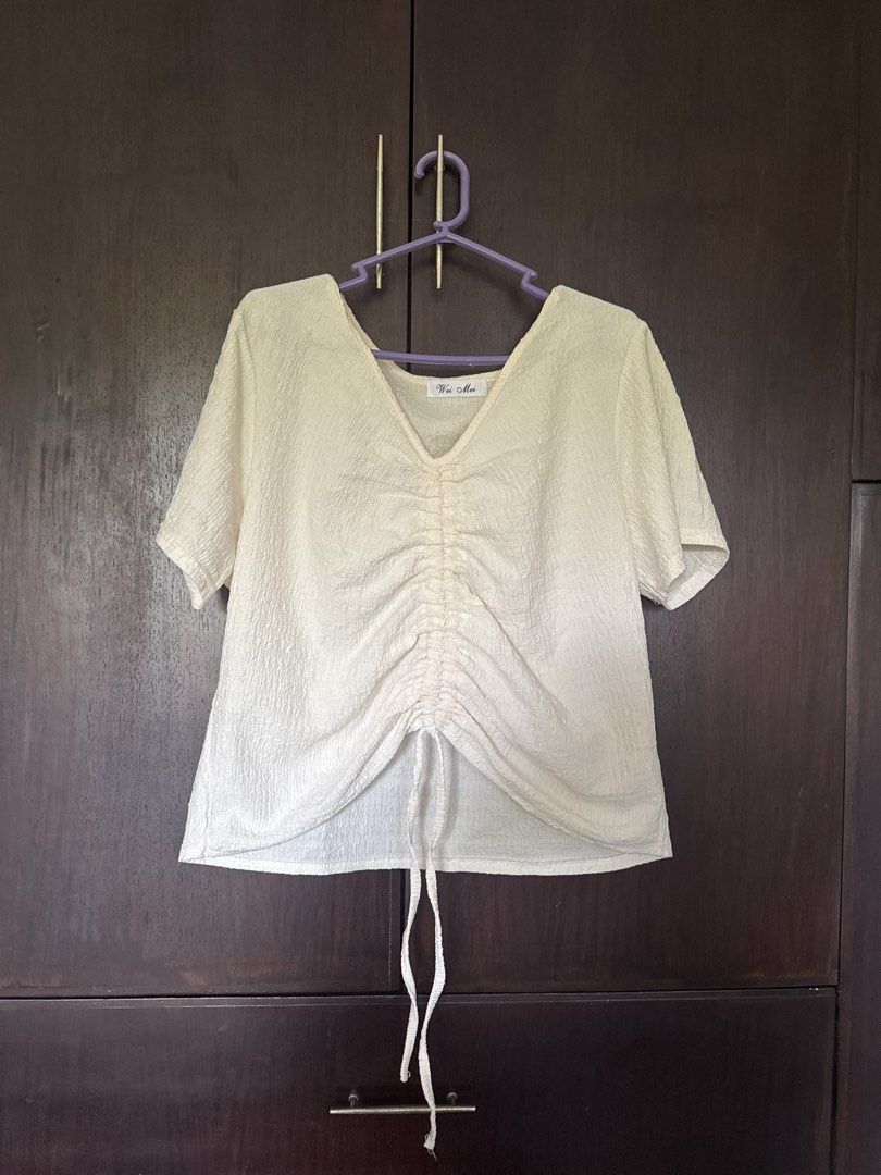 Wei Mei Cream V-Neck Ruched Front Top (Category: Blouses) located in Santo Tomas. Submitted by toughu (Listing ID 1468955160, Image 1). Description: - Brand: Wei Mei - Color: Cream - Sleeve Length: Short sleeve - Neckline: V-neck - Details: Adjustable drawstring ruched front with hem ties - Fabric: All-over textured crinkle material - Style: Casual, versatile, and easy to match with jeans or skirts.