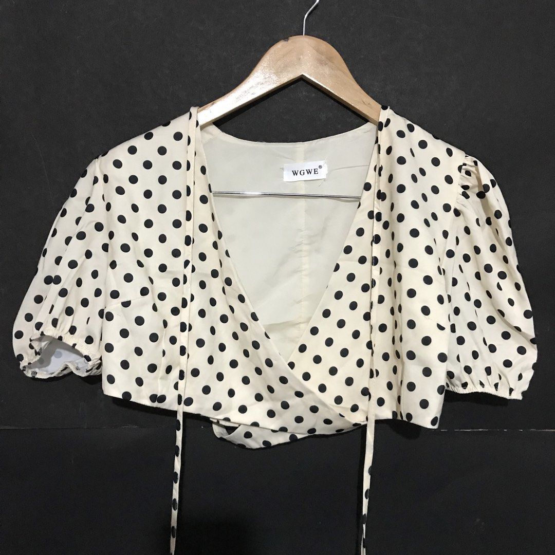 WGWE Polka Dot Wrap Crop Top Puff Sleeves (Category: Blouses) located in Roxas City. Submitted by jijishandmade.handpicked (Listing ID 1468989599, Image 2). Description: - Color/Pattern: Cream with black polka dots - Design: Wrap front style with self-tie waist strings - Sleeves: Short puff sleeves with elastic cuffs - Comfort: Includes inner lining - Branding: WGWE brand tag at the neckline.