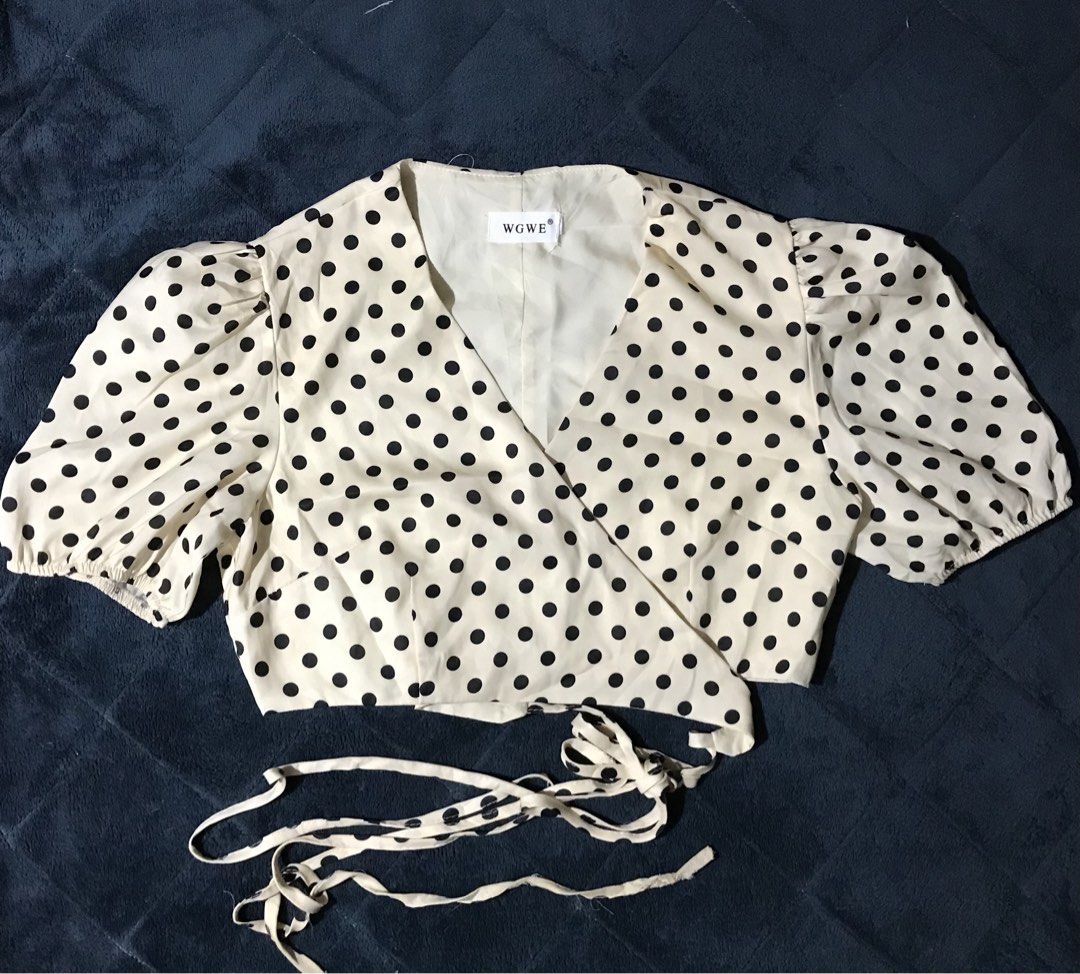 WGWE Polka Dot Wrap Crop Top Puff Sleeves (Category: Blouses) located in Roxas City. Submitted by jijishandmade.handpicked (Listing ID 1468989599, Image 1). Description: - Color/Pattern: Cream with black polka dots - Design: Wrap front style with self-tie waist strings - Sleeves: Short puff sleeves with elastic cuffs - Comfort: Includes inner lining - Branding: WGWE brand tag at the neckline.