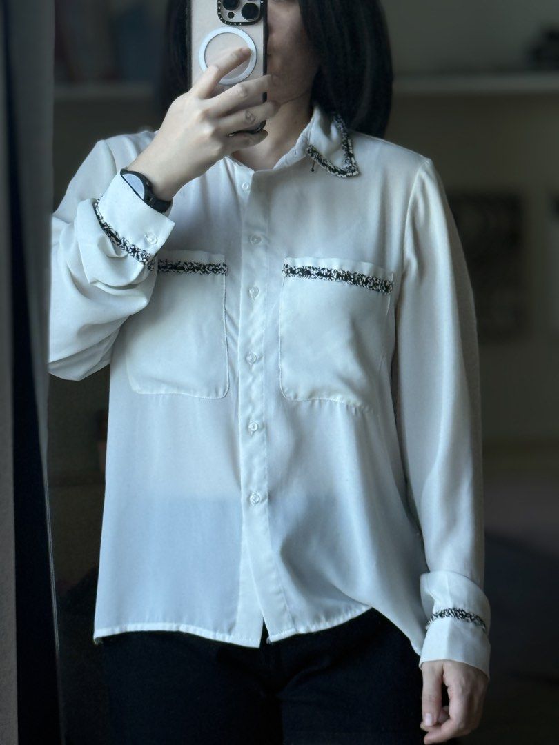 White Button-Up Blouse with Black Tweed Trim Detailing (Category: Blouses) located in Pasig City. Submitted by laagn.ph (Listing ID 1469089550, Image 3). Description: - Color: White with black-and-white textured tweed trim - Design: Button-up with double chest pockets and tweed accents on collar, cuffs, and pocket flaps - Fabric: Lightweight and drapes nicely - Style: Versatile office-to-dinner top, pairs easily with trousers or denim - Condition