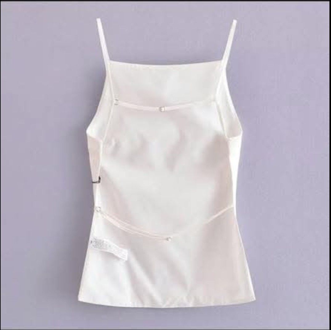 White camisole top backless (Category: Sleeveless) located in Makati City. Submitted by galaxyjaykim (Listing ID 1469133945, Image 2). Description: - Color: White - Neckline: Square neck with thin, adjustable cross-back spaghetti straps - Material: Smooth, comfortable fabric - Style: Clean minimalist everyday basic - Pairing: Perfect with high-waisted jeans or skirts - Condition: Brand new with tag attached near the bottom hem.