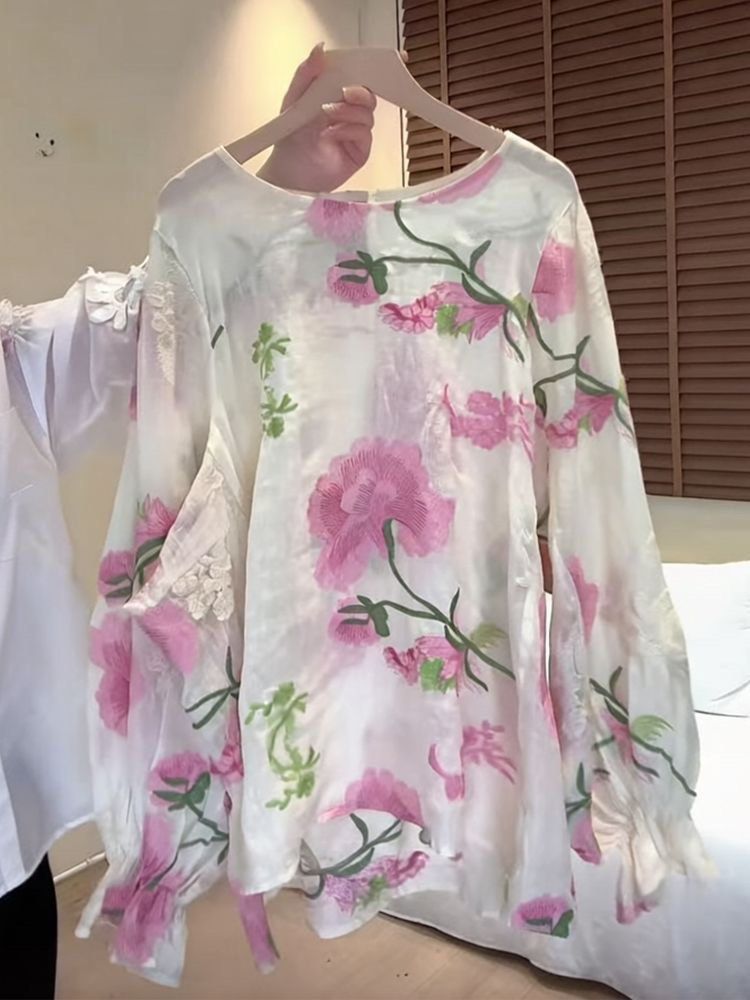 White Floral Embroidered Long Sleeve Blouse (Category: Longsleeves) located in Taguig. Submitted by mengxir20193848 (Listing ID 1468988421, Image 1). Description: - Color: White with pink and green floral embroidery - Material: Sheer textured fabric with subtle floral patterns - Design: Round neckline, back button closure, and ruffled sleeve cuffs - Fit: Loose and flowy - Perfect for: Spring outfits and casual chic looks.