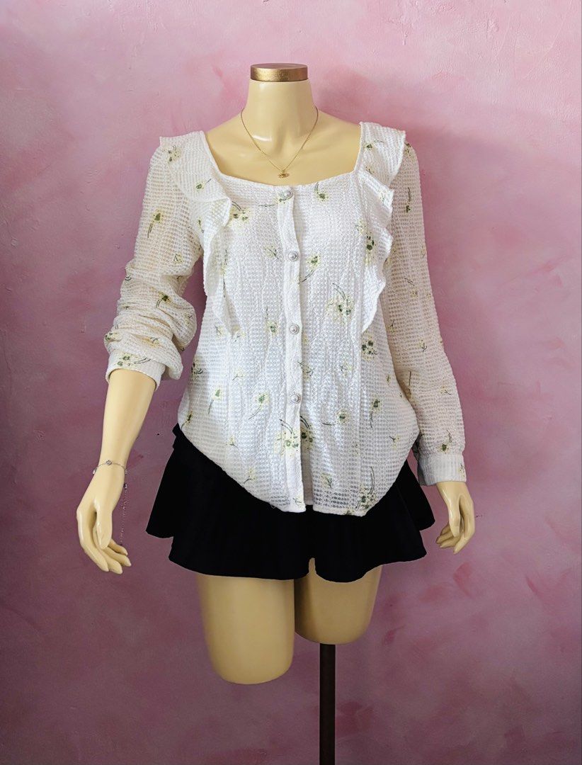 White Floral Square Neck Ruffle Blouse (Category: Blouses) located in Lipa City. Submitted by classyces24 (Listing ID 1469047209, Image 1). Description: - Color/Pattern: White with a delicate green floral print - Design: Square neckline with ruffle trim on the chest and shoulders - Closure: Front button-up with elegant pearl-style buttons - Material: Lightweight, textured waffle-knit fabric - Versatility: Easy to pair with both skirts and trouser