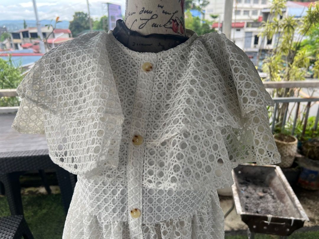 White lace ruffle midi dress with buttons (Category: Dresses) located in Caloocan City. Submitted by thewardrobe05 (Listing ID 1467376239, Image 3). Description: - Color: White - Material: Patterned lace fabric - Design: Round neckline with full front button closure - Sleeves: Short layered ruffle sleeves - Fit: Fitted waist with a flared midi skirt - Versatility: Ideal for daytime events, dates, or weekend brunches; easy to pair with flats or sa