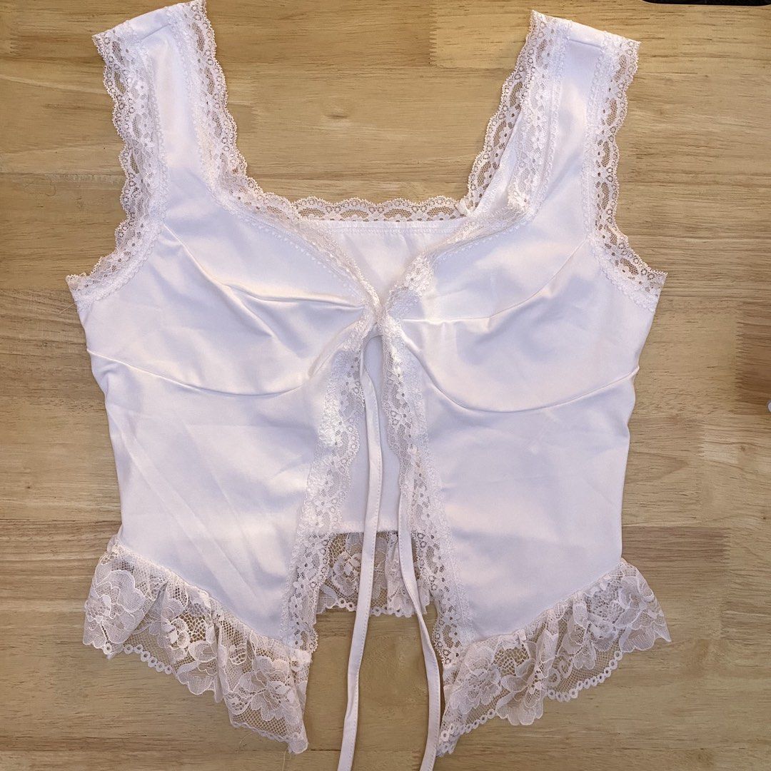 White Lace Trim Tie Front Crop Top (Category: Sleeveless) located in Cavite. Submitted by helloize (Listing ID 1466630976, Image 1). Description: White sleeveless crop top with delicate lace trim along the square neckline and hem. Features a tie-front closure with a dainty ribbon. Soft fabric, great for layering or wearing on its own during warm weather. Clean condition, no flaws noticed. Super nice fabric.