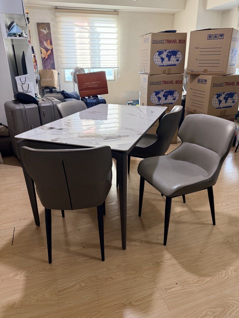 White Marble Finish Dining Table with 4 Grey Chairs (Category: Tables & Sets) located in Pasig City. Submitted by carlodejesus (Listing ID 1468932504, Image 1). Description: VICTORIA MONDIALE DINING TABLE & 4 CHAIRS Moving out sale, migrating. Package Price: ₱18,000 Specifications: Table Size: 140 × 80 cm 12mm Thick Sintered Stone Tabletop with Marble Finish Powder-Coated Metal Legs Modern dining set with clean, space-saving design - White marble