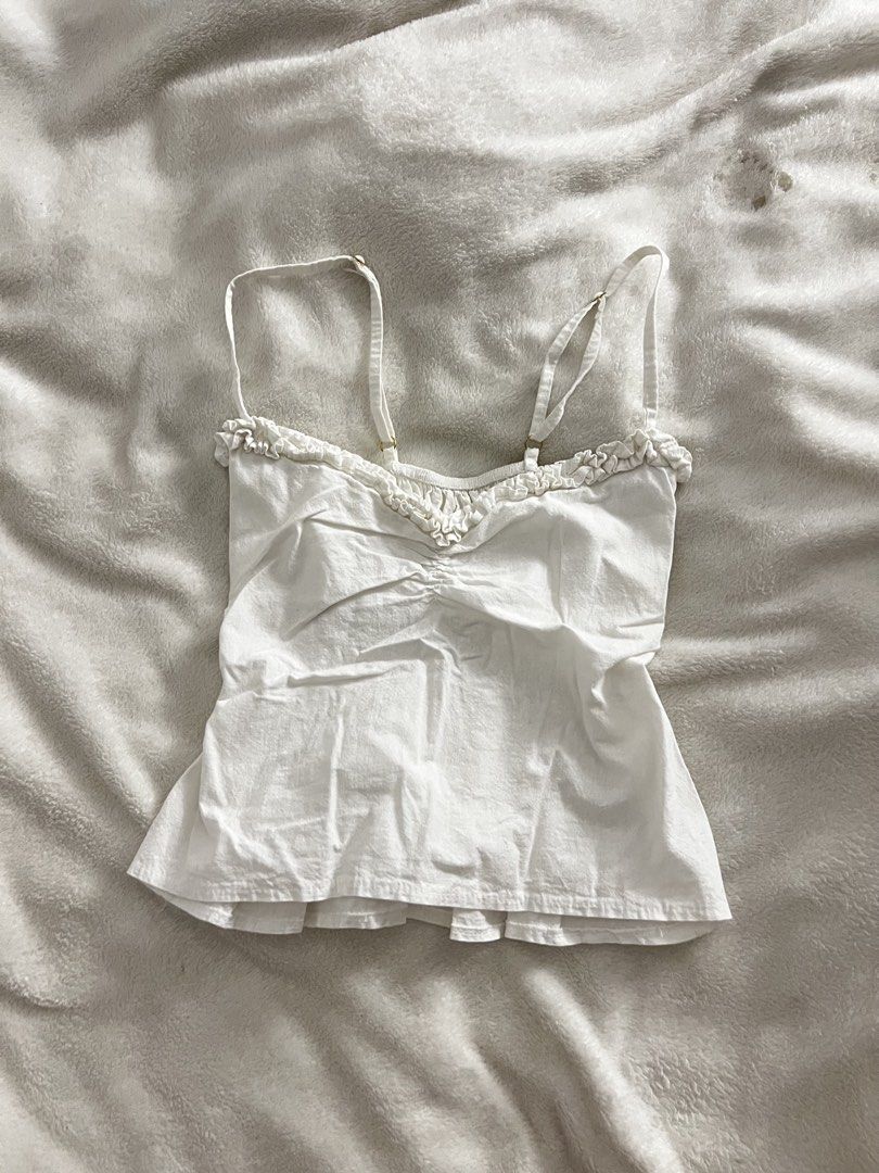 White Ruffle Trim Cami Top with Smocked Back (Category: Sleeveless) located in San Leonardo. Submitted by hmmmhehe (Listing ID 1469053405, Image 1). Description: - Color: White - Style: Ruffled neckline, gathered center front, and flared peplum hem - Fit: Fully smocked elastic back for a comfortable stretch - Features: Adjustable shoulder straps and lightweight fabric - Best for: Warm weather, layering, or pairing with denim shorts.
