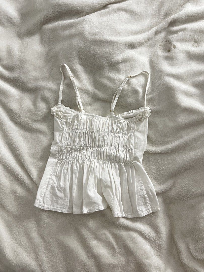 White Ruffle Trim Cami Top with Smocked Back (Category: Sleeveless) located in San Leonardo. Submitted by hmmmhehe (Listing ID 1469053405, Image 2). Description: - Color: White - Style: Ruffled neckline, gathered center front, and flared peplum hem - Fit: Fully smocked elastic back for a comfortable stretch - Features: Adjustable shoulder straps and lightweight fabric - Best for: Warm weather, layering, or pairing with denim shorts.