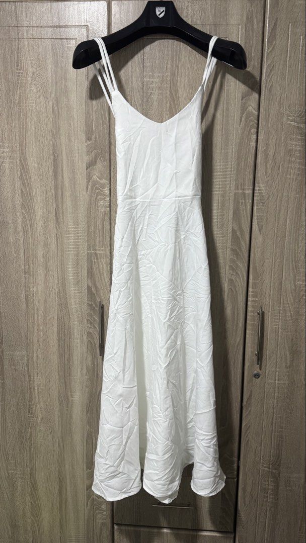 White Spaghetti Strap Long Dress (Category: Dresses) located in Davao. Submitted by wisedeer-bcd8 (Listing ID 1469083517, Image 1). Description: Plain white long dress with thin double straps. Cross-back strap detail. V-neckline in front and back. Fitted waist with a flared skirt falling down to midi or maxi length. Fabric looks lightweight and smooth. Simple, clean look for casual days or outdoor events. Just needs a quick iron to smooth out the