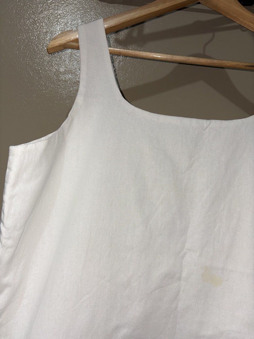 White Square Neck Tank Top (Category: Sleeveless) located in Caloocan City. Submitted by stella_mari27 (Listing ID 1469105170, Image 3). Description: - Color: Plain white - Style: Square neckline, thick straps, straight hem - Material: Sturdy, great for layering or hot days - Flaw: Small yellowish stain near the front center (needs a proper wash).