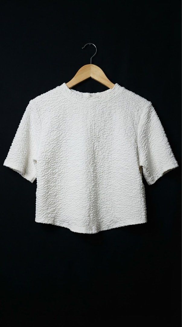 White textured short sleeve blouse with asymmetrical front seam (Category: Blouses) located in Cavite. Submitted by grandearth.39df3f (Listing ID 1468955830, Image 2). Description: - Color: Crisp white - Fabric: Soft, stretchy, all-over textured bubbly material - Fit: Structured boxy fit with a round neckline - Design: Unique asymmetrical seam on the right front and slightly curved center hem - Versatility: Super comfortable for daily wear, easil