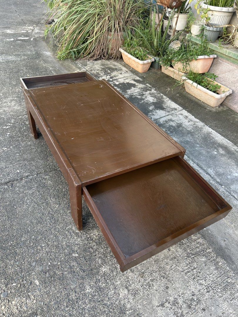 Wooden Coffee Table with Dual Pull-Out Side Trays (Category: Tables & Sets) located in Manila. Submitted by jonalyn36017 (Listing ID 1468978710, Image 2). Description: - Solid wooden coffee table in a rich dark brown finish - Features 2 built-in pull-out trays on opposite sides for extra space - Sturdy frame supported by 4 solid block legs - Condition: Used with visible surface scratches, scuffs, and signs of daily wear - Pickup or delivery optio