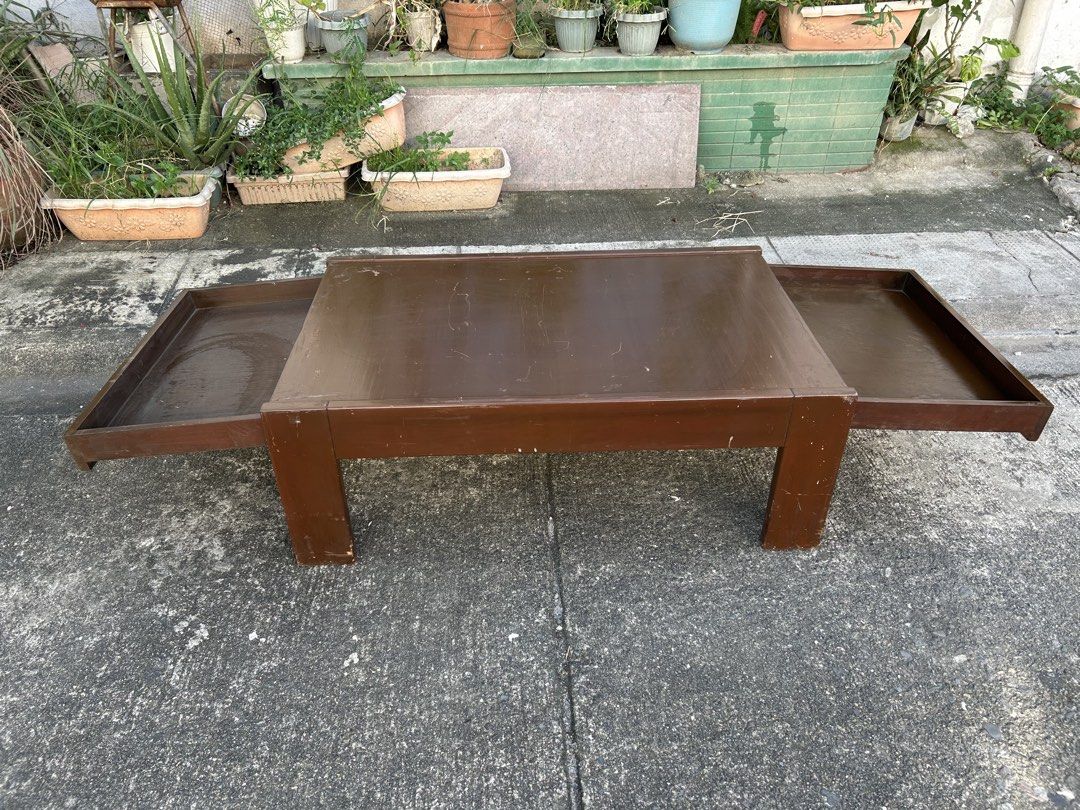 Wooden Coffee Table with Dual Pull-Out Side Trays (Category: Tables & Sets) located in Manila. Submitted by jonalyn36017 (Listing ID 1468978710, Image 1). Description: - Solid wooden coffee table in a rich dark brown finish - Features 2 built-in pull-out trays on opposite sides for extra space - Sturdy frame supported by 4 solid block legs - Condition: Used with visible surface scratches, scuffs, and signs of daily wear - Pickup or delivery optio