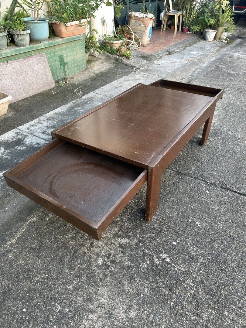 Wooden Coffee Table with Dual Pull-Out Side Trays (Category: Tables & Sets) located in Manila. Submitted by jonalyn36017 (Listing ID 1468978710, Image 3). Description: - Solid wooden coffee table in a rich dark brown finish - Features 2 built-in pull-out trays on opposite sides for extra space - Sturdy frame supported by 4 solid block legs - Condition: Used with visible surface scratches, scuffs, and signs of daily wear - Pickup or delivery optio