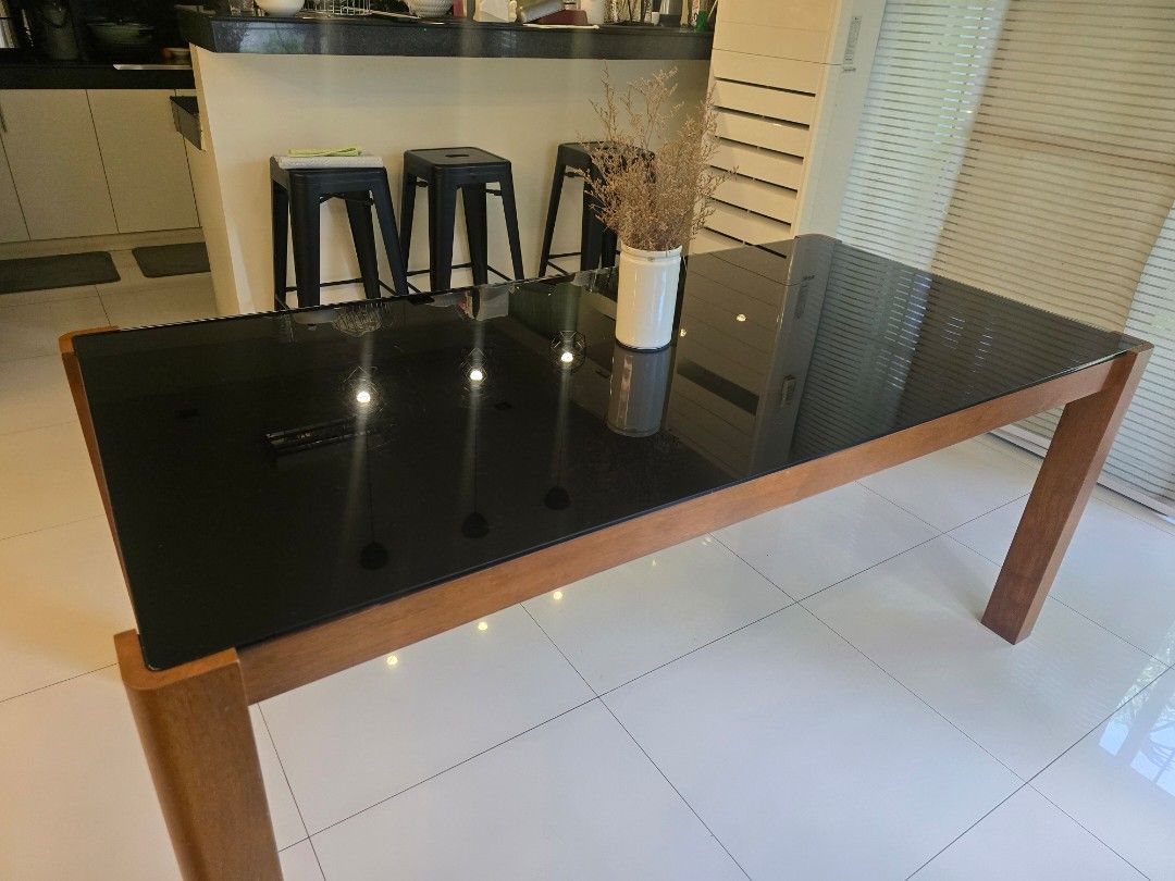 Wooden dining table with black glass top (Category: Tables & Sets) located in Paranaque City. Submitted by buzzybizness (Listing ID 1468986427, Image 3). Description: - Sturdy wooden (solid wood) frame - Sleek dark tempered glass tabletop with black film finish - 72inch length. - Spacious 6-seater design, perfect for family meals and entertaining Condition: - The table is in excellent condition - Minor wear marks on the glass film. Selling as-is.