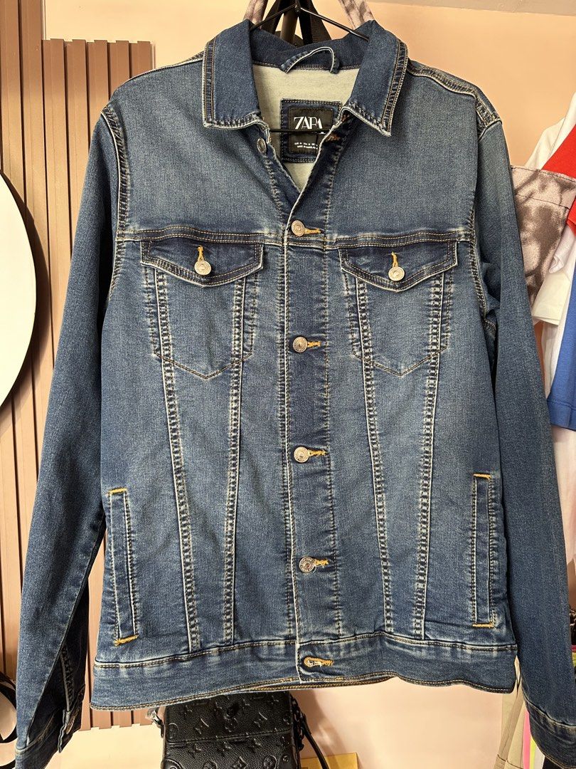 Zara Denim Jacket Blue (Category: Coats, Jackets and Outerwear) located in Vinzons. Submitted by melodylarg85741 (Listing ID 1468983832, Image 1). Description: - Brand: Zara - Wash: Medium blue with contrast stitching - Size: Medium - Closure: Front metal buttons - Pockets: Two buttoned chest flap pockets and two lower welt pockets - Fit: Standard fit - Condition: Great layering piece for cooler days.