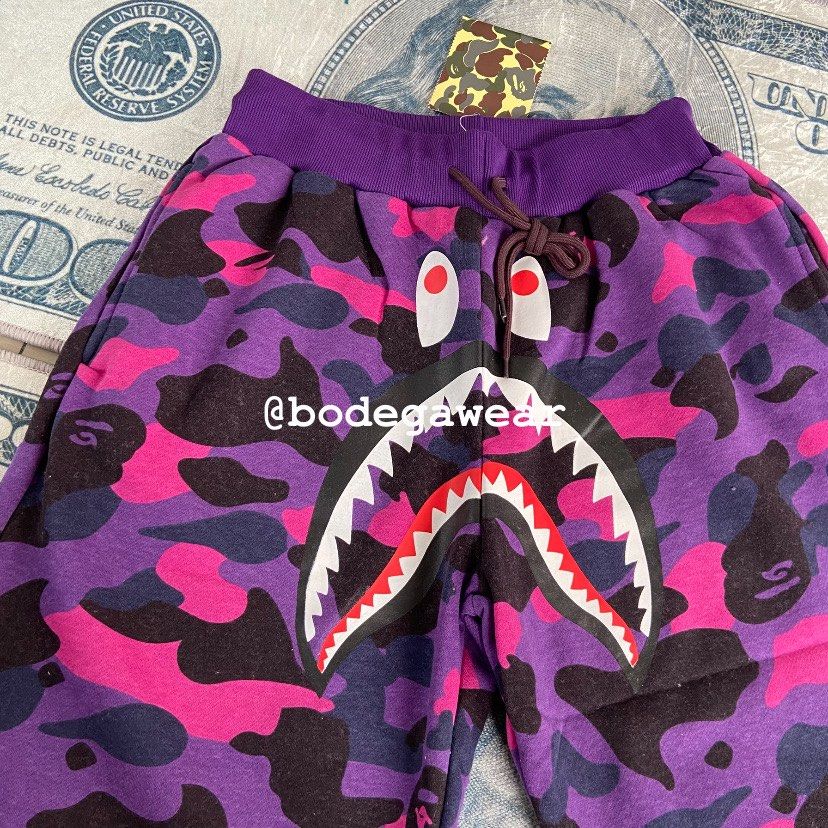 A Bathing Ape Purple Camo Shark Shorts (Category: Shorts) located in Manila. Submitted by bodegawear_mnl (Listing ID 1465409680, Image 2). Description: - Brand: BAPE (A Bathing Ape) - Item: Purple Camo Shark Sweat Shorts - Size: Small - Condition: Brand new with original tags attached - Features: Iconic shark face graphic with red/white teeth, soft fleece lining, drawstring waist, and back pocket with ape head tag - Authenticity: 100% authentic s