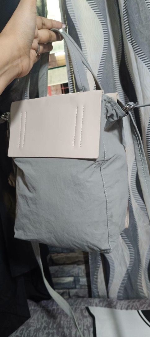 Acne Studios Baker Out Medium Tote (Category: Tote Bags) located in Manila. Submitted by _outofthecloset. (Listing ID 1465421986, Image 2). Description: - Brand: Acne Studios - Model: Baker Out Medium Tote - Color: Grey and beige - Material: Cotton body with premium leather-look pocket and handles - Features: Zippered front compartment, structured front flap with printed logo text, and interior branding tag - Versatility: Includes top handles and