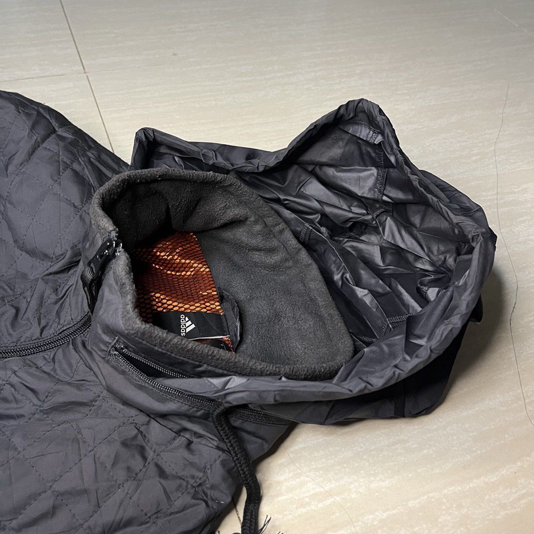 Adidas Black Quilted Zip Jacket with Hood (Category: Coats, Jackets and Outerwear) located in Manila. Submitted by kukolmarc (Listing ID 1465432373, Image 2). Description: - Brand: Adidas - Color: Black - Condition: Excellent / Pre-loved - Design: Quilted outer shell with subtle sleeve stripes and printed logo - Comfort & Warmth: Built-in hood with fleece-lined collar and orange mesh interior - Pockets: Convenient zipper pockets on both chest and