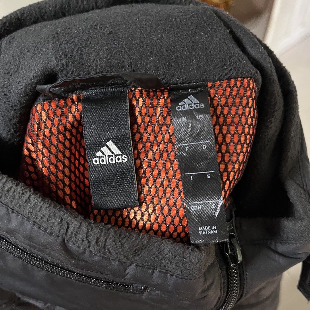 Adidas Black Quilted Zip Jacket with Hood (Category: Coats, Jackets and Outerwear) located in Manila. Submitted by kukolmarc (Listing ID 1465432373, Image 3). Description: - Brand: Adidas - Color: Black - Condition: Excellent / Pre-loved - Design: Quilted outer shell with subtle sleeve stripes and printed logo - Comfort & Warmth: Built-in hood with fleece-lined collar and orange mesh interior - Pockets: Convenient zipper pockets on both chest and