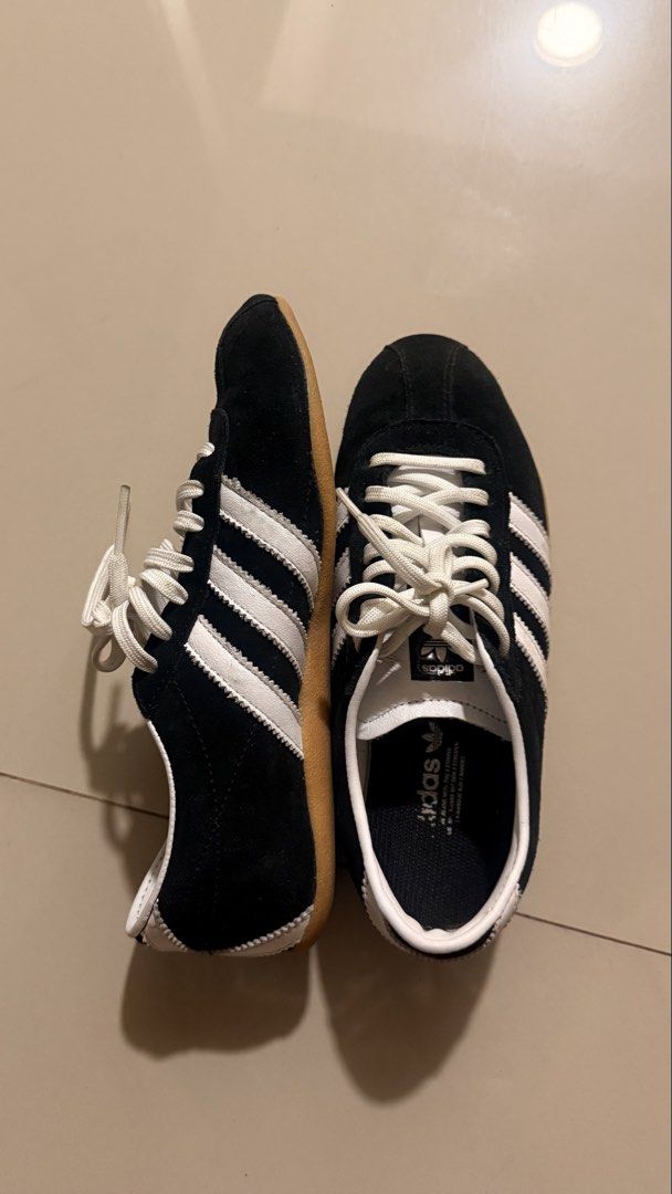 Adidas Tokyo Black White Sneakers (Category: Sneakers) located in Quezon City. Submitted by bea3s (Listing ID 1465486894, Image 2). Description: - Brand/Model: Adidas Classic Black Suede Sneakers - Details: White stripes, white laces, and iconic gold Tokyo lettering on the side - Sole: Durable gum rubber sole with minimal wear - Interior: White leather collar with Adidas trefoil logo on the tongue and insole - Condition: Clean overall, well-maint