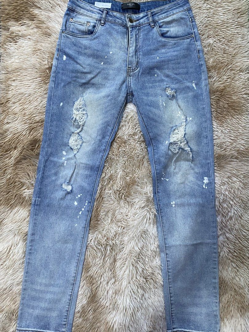 AMIRI Distressed Paint Splatter Jeans Size 32 (Category: Jeans) located in Santa Ana. Submitted by tunes_vtg (Listing ID 1465462539, Image 1). Description: - Brand: AMIRI - Color/Wash: Light blue wash - Size: 32 - Details: Paint splatter effect, distressed ripped knees, and frayed areas - Construction: Classic five-pocket style with button fly - Branding: Leather waist label and custom branded hardware - Condition: Clean hems, well-maintained - N