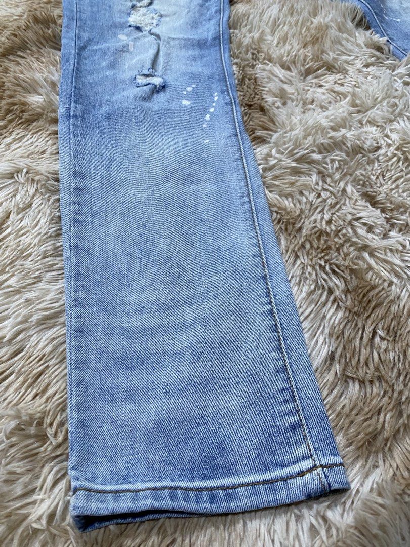 AMIRI Distressed Paint Splatter Jeans Size 32 (Category: Jeans) located in Santa Ana. Submitted by tunes_vtg (Listing ID 1465462539, Image 2). Description: - Brand: AMIRI - Color/Wash: Light blue wash - Size: 32 - Details: Paint splatter effect, distressed ripped knees, and frayed areas - Construction: Classic five-pocket style with button fly - Branding: Leather waist label and custom branded hardware - Condition: Clean hems, well-maintained - N