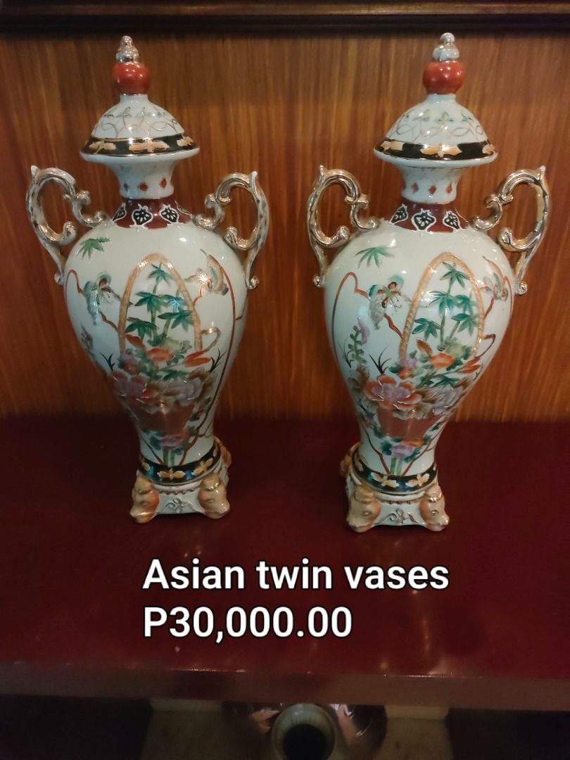 Asian Twin Vases with Lids (Category: Vases & Decorative Bowls) located in Caloocan City. Submitted by rise-edge (Listing ID 1465451245, Image 1). Description: Pair of decorative Asian twin vases featuring traditional floral and botanical hand-painted patterns with gilt accents. Includes matching removable lids. Double-handled design on each vase. Stands on four small decorative feet. Height 20 inches, body diameter 9 inches, base 5 by 5 inches..