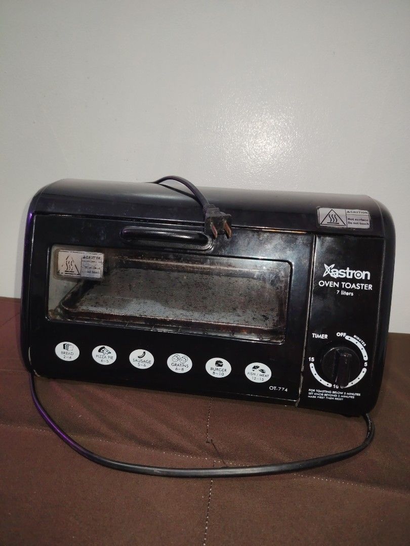 Astron Oven Toaster (Category: Ovens & Toasters) located in Mandaluyong City. Submitted by declutter_kween (Listing ID 1465526178, Image 2). Description: Astron oven toaster, model OT-774, capacity 7 liters. Black exterior housing with front control knobs and timer settings up to 15 minutes. Includes interior wire rack and baking tray. Interior walls show heavy use with baked-on grease and staining. Heating elements operational. Standard electric