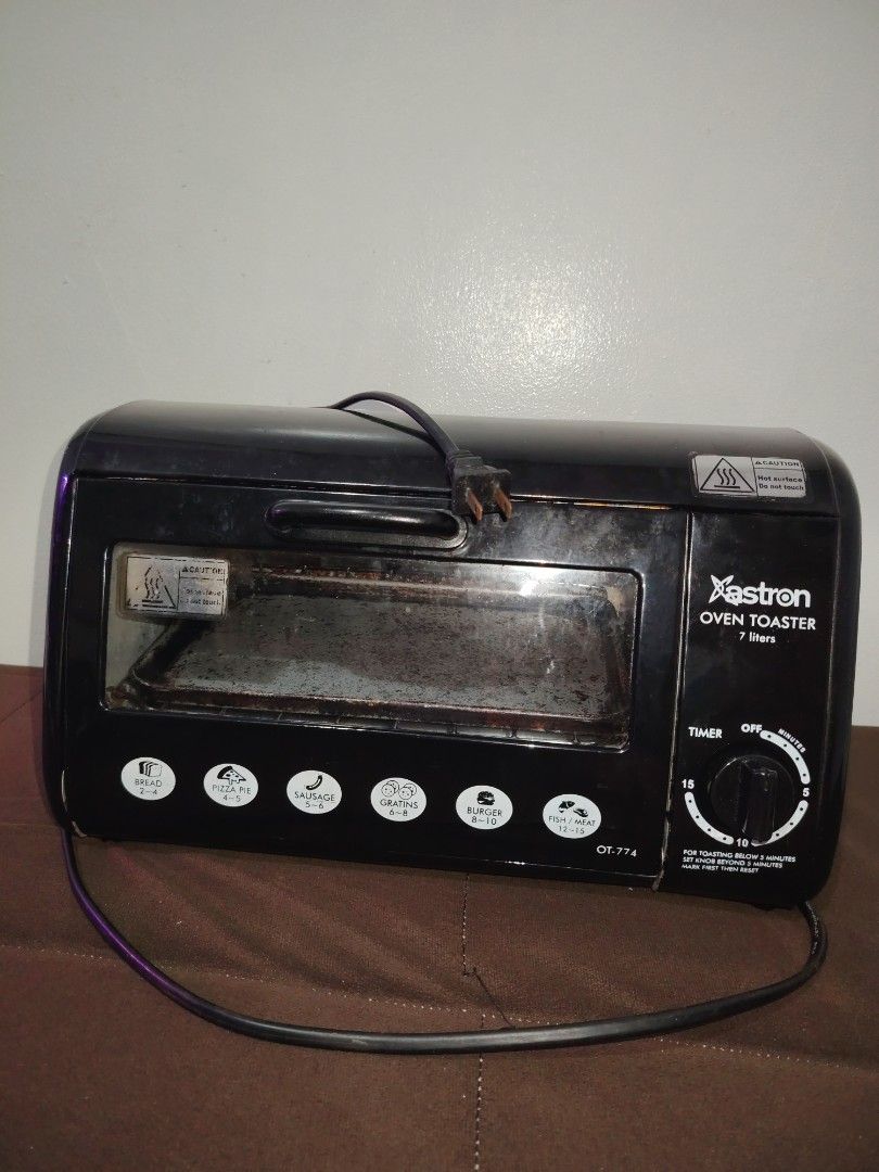 Astron Oven Toaster (Category: Ovens & Toasters) located in Mandaluyong City. Submitted by declutter_kween (Listing ID 1465526178, Image 1). Description: Astron oven toaster, model OT-774, capacity 7 liters. Black exterior housing with front control knobs and timer settings up to 15 minutes. Includes interior wire rack and baking tray. Interior walls show heavy use with baked-on grease and staining. Heating elements operational. Standard electric