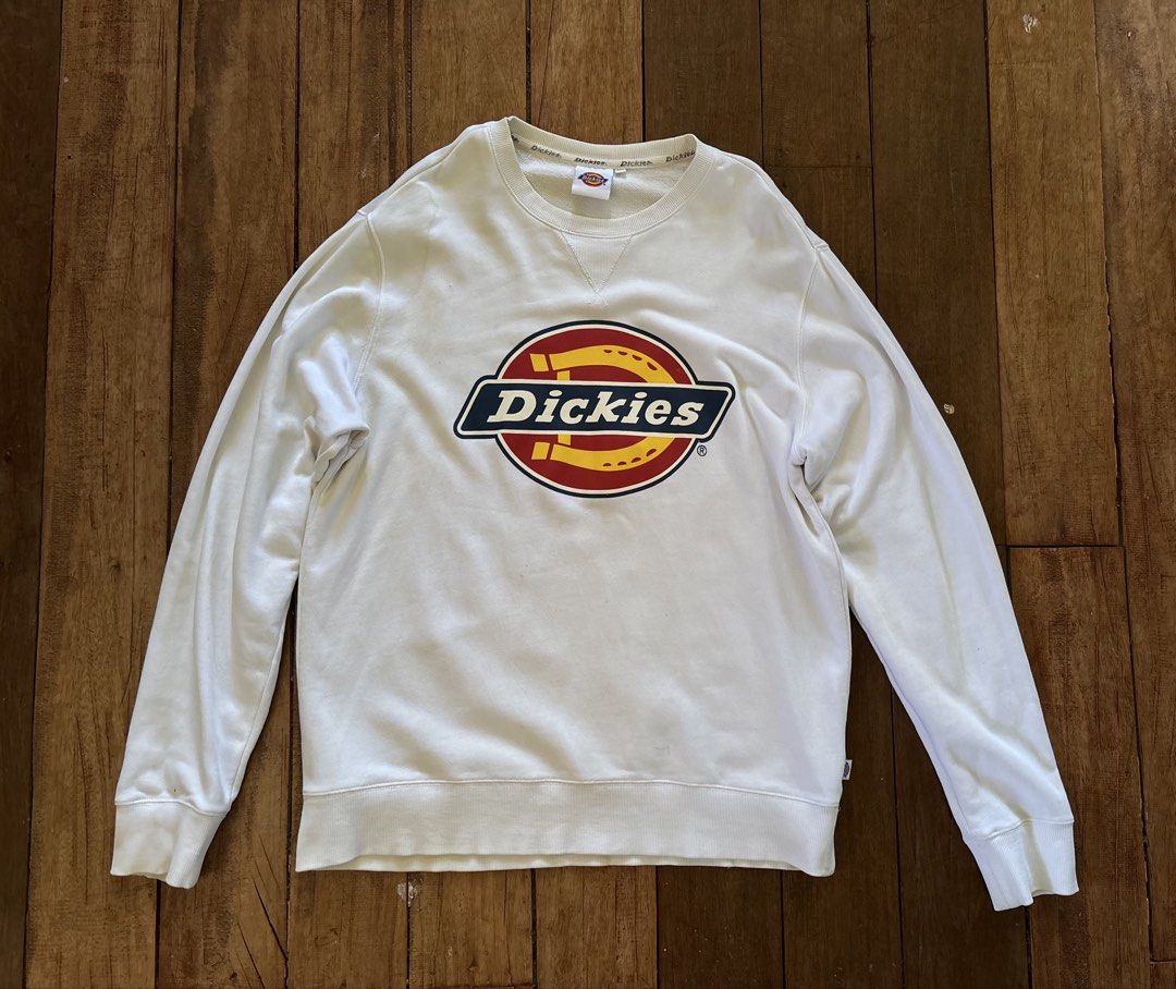 Authentic Dickies Pullover (Category: Coats, Jackets and Outerwear) located in Tabuk. Submitted by xosove (Listing ID 1465404966, Image 1). Description: White Dickies crewneck sweatshirt featuring the classic Dickies logo prominently printed across the chest. It has long sleeves, ribbed cuffs, and a ribbed waistband for a comfortable fit. The sweatshirt has a simple, clean, casual design with a slightly relaxed silhouette, making it easy to pair 