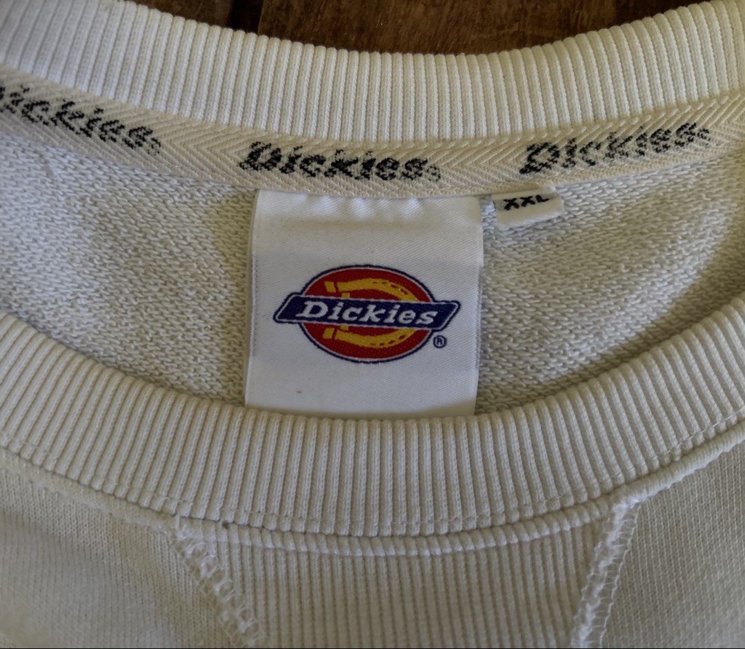 Authentic Dickies Pullover (Category: Coats, Jackets and Outerwear) located in Tabuk. Submitted by xosove (Listing ID 1465404966, Image 2). Description: White Dickies crewneck sweatshirt featuring the classic Dickies logo prominently printed across the chest. It has long sleeves, ribbed cuffs, and a ribbed waistband for a comfortable fit. The sweatshirt has a simple, clean, casual design with a slightly relaxed silhouette, making it easy to pair 