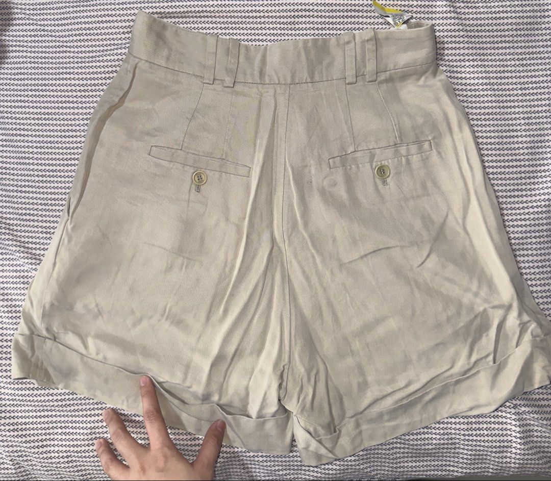 Babaton Talula Four Pleated Beige Shorts Size 4 (Category: Shorts) located in Santa Ana. Submitted by fatikilla (Listing ID 1465439039, Image 3). Description: - Brand/Style: Talula Babaton tailored shorts - Color: Versatile neutral beige - Size: 4 - Design: Pleated front with cuffed hems - Details: Zip fly, waistband with belt loops, and back welt pockets with button closures - Condition: Excellent.