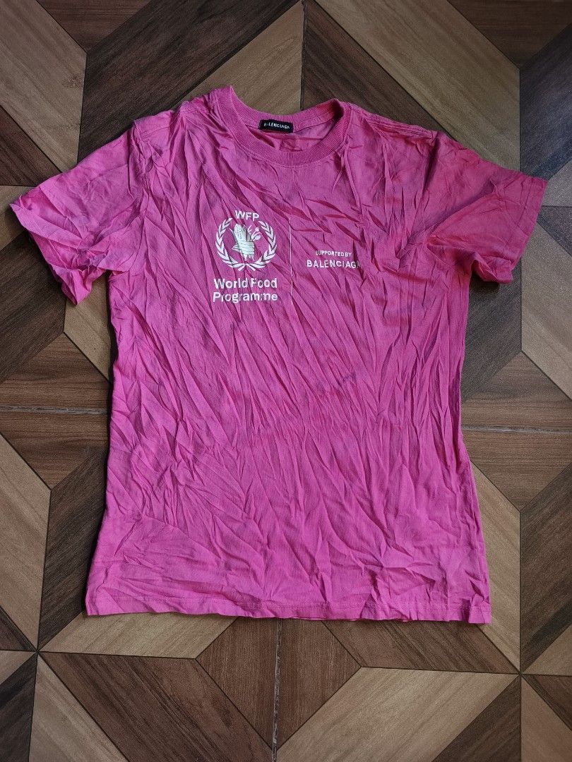 Balenciaga WFP World Food Programme (Category: Shirts) located in Zamboanga. Submitted by d2977250664046 (Listing ID 1465535547, Image 1). Description: - Brand: Balenciaga x World Food Programme (WFP) - Color: Bright pink with large front graphic - Size: XL 20x27 - Details: Ribbed crew neck collar, interior black tag with production and care info - Origin: Made in Italy - Condition: Premium designer piece with bold charitable branding.