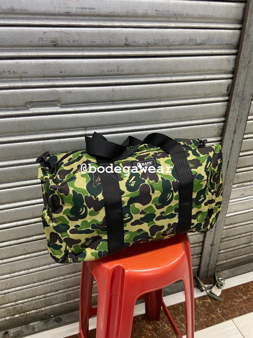 BAPE Camo Duffle Bag Green and Black (Category: Sling Bags) located in Manila. Submitted by bodegawear_mnl (Listing ID 1465407578, Image 1). Description: - Available Colors: Green Camo and Black Camo - Material: Durable, high-quality canvas with sturdy black carrying handles - Features: Bold BAPE logo patches on the front and a detachable shoulder strap (included with the black bag) - Versatility: Perfect size for the gym, travel, or everyday use