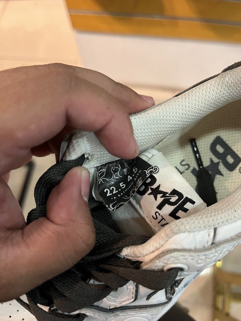 BAPE Sta Low White Grey Size 22.5cm US 4.5 (Category: Sneakers) located in Tabuk. Submitted by collectors_thrift_shop (Listing ID 1465464140, Image 2). Description: - Brand: A Bathing Ape (BAPE) - Style: Low-top sneakers - Color: White and grey with dark grey laces - Size: 22.5cm / US 4.5 - Material: Embossed camo leather upper with dark suede heel tabs - Details: Signature metallic star logo on sides, yellow ape head collar tag, and embroidered 