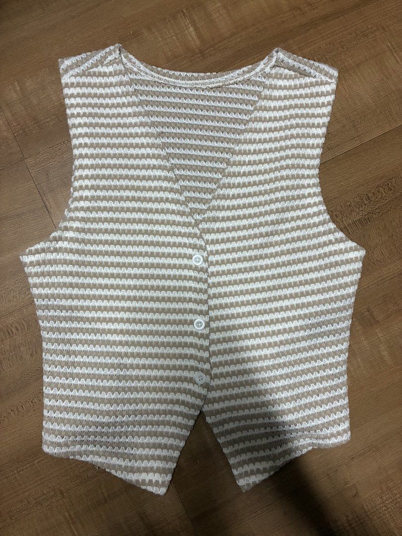 Beige and White Striped Knit Button Vest (Category: Sleeveless) located in Quezon City. Submitted by habits.mnl (Listing ID 1465479647, Image 1). Description: - Color/Pattern: Classic beige and white horizontal stripes - Design: V-neckline with a 3-button front closure and stylish split front hem - Material: Lightweight, breathable knitted texture - Styling: Great for layering over basic tees/shirts or wearing on its own.