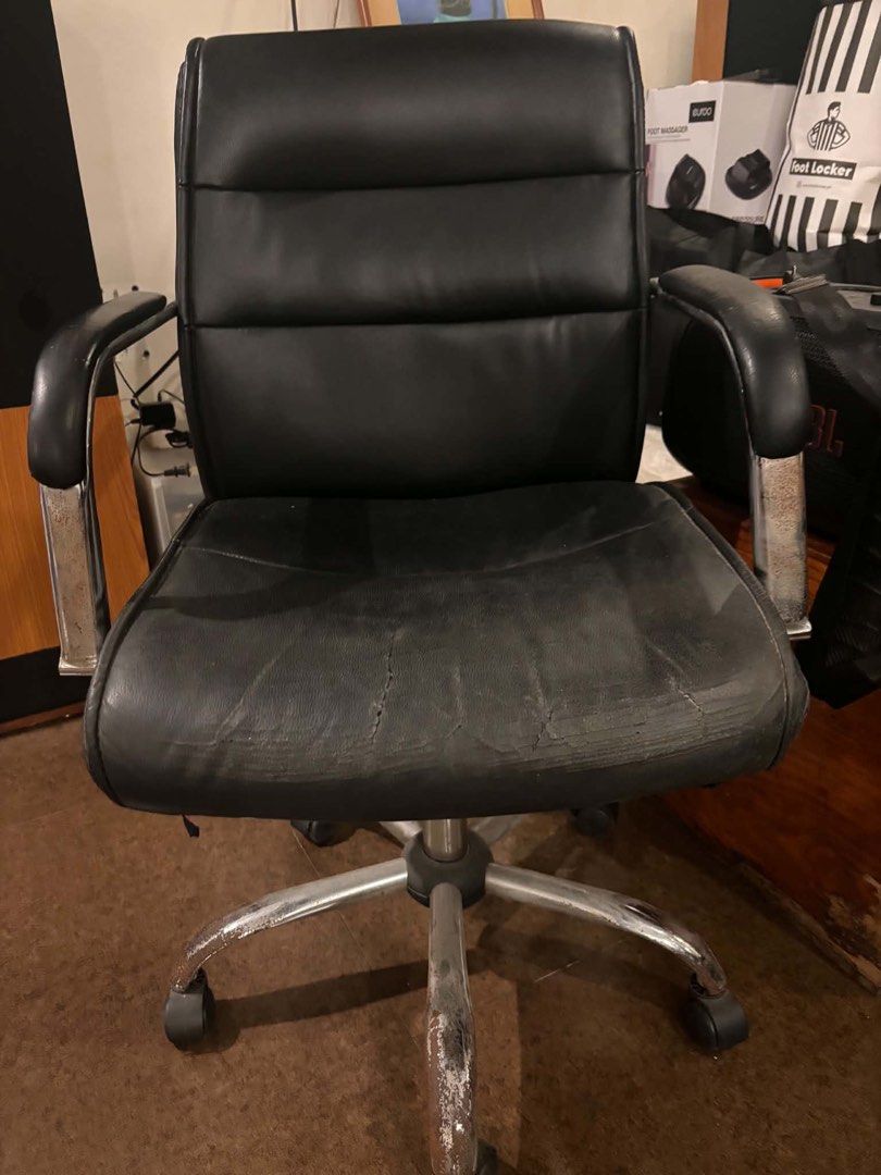 Black leather office chair with chrome wheels (Category: Office Furniture & Fixtures) located in Manila. Submitted by kelsgonzzzales26 (Listing ID 1465450634, Image 1). Description: - Color & Material: Black faux leather executive office chair - Mobility & Base: Rolling casters on a 5-star chrome base - Condition: Noticeable cracking and peeling on the front seat edge, with wear on the armrests and chrome finish.