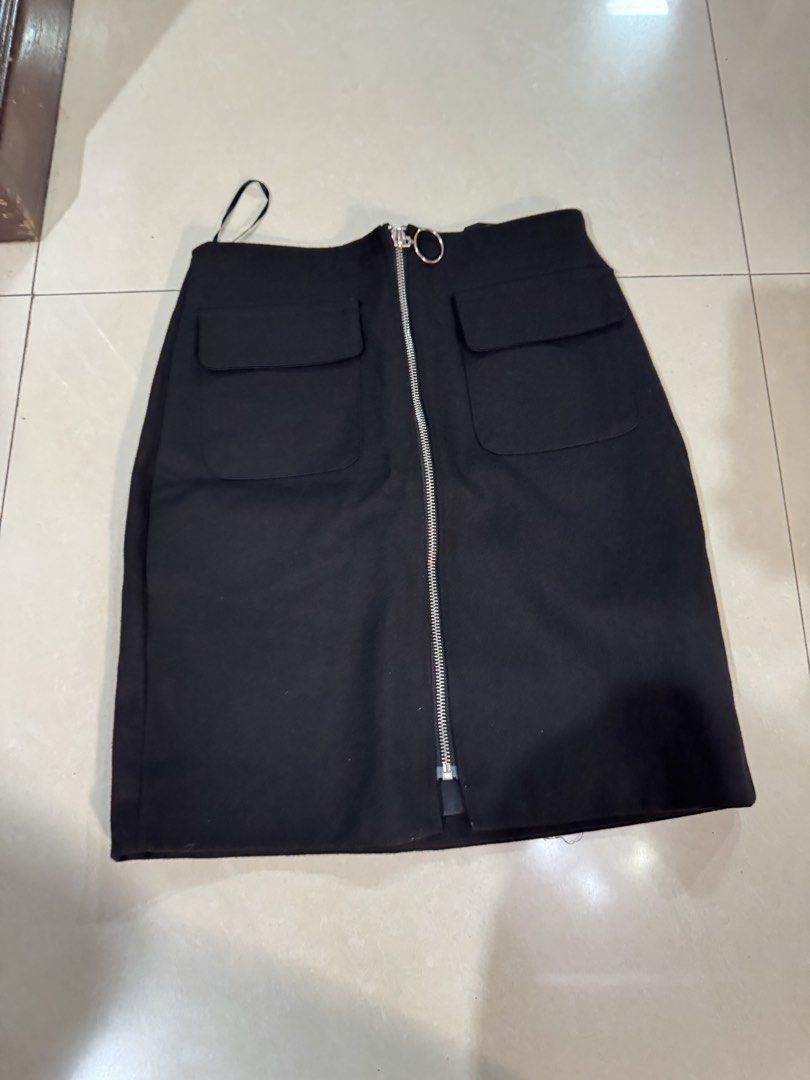 Black Zipper Front Skirt (Category: Skirts) located in Quezon City. Submitted by sweetlyluxe (Listing ID 1465492796, Image 1). Description: - Brand: HANHAO - Size: M - Color: Plain Black - Features: Front zipper with large ring pull, two front patch pockets with flaps, back darts for a flattering shape - Condition: Clean inside lining, brand label intact - Style: Versatile and chic, easy to pair with any top.