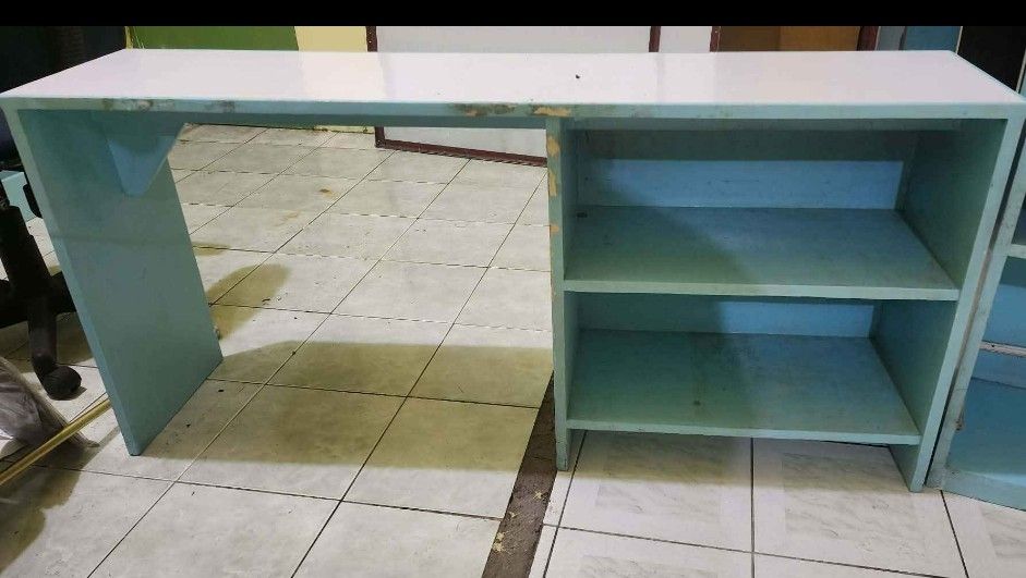 Blue and White Study Desk with Storage Shelves (Category: Office Furniture & Fixtures) located in Paranaque City. Submitted by yumme (Listing ID 1465465926, Image 3). Description: - Color: Blue and white - Material: Solid wood construction - Storage: Two open storage shelves on the right side - Design: Long rectangular tabletop - Condition: Good overall, with some chipped paint along the front edge - Ideal for: Bedroom or home office setup.